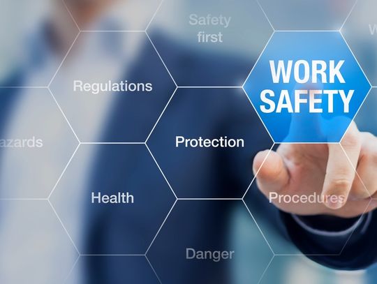 A businessman reaches over and presses a hexagon on a grid labeled "Work Safety." Other ones feature other words.