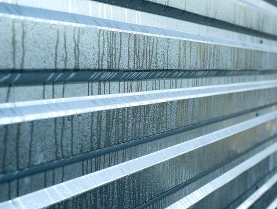 A close-up of a corrugated metal panel with condensation and vertical streaking across the surface.
