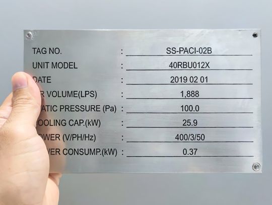 A close-up view shows a person holding a stainless steel nameplate that lists items such as tag no., date, and unit model.