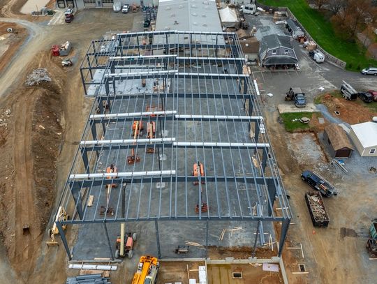 A construction site featuring the metal frame of a building. Various equipment and materials are present.