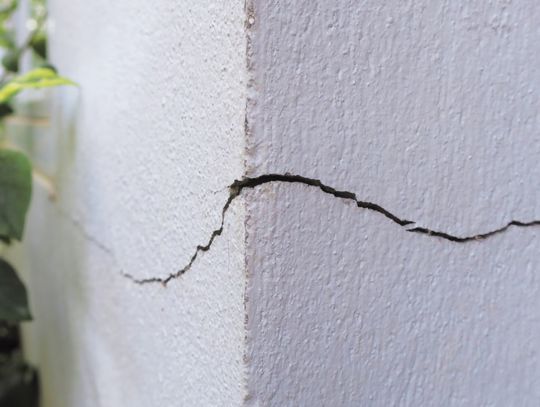 A closeup on the corner of a home's foundation. There is a very noticeable crack running along the concrete.