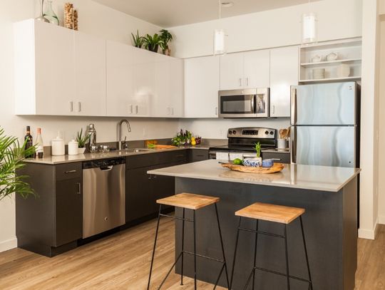 A residential kitchen with a refrigerator, an island, and multiple cabinets along the wall.