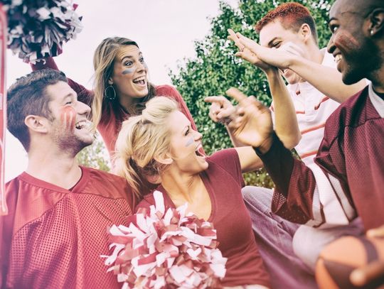 A group of college students is excited for the football game, all wearing red to show their school spirit.