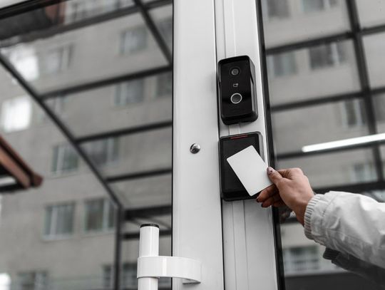 A person holding an access control keycard up to an AI sensor to gain entry to the business building.