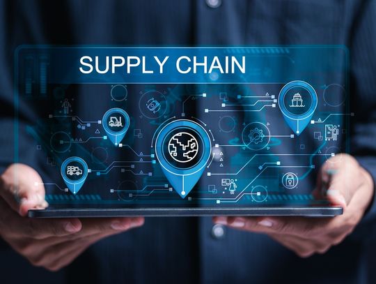 Close-up of hands holding a tablet with the words "Supply Chain" above it and a digital representation of the chain.