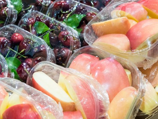 Plastic containers hold sliced red apples and whole cherries; no labels are visible on the packaging.