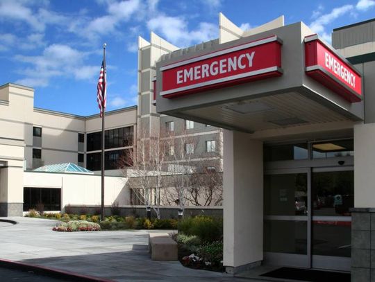 The entrance to the emergency room at a hospital is marked by a red and white sign that says EMERGENCY on it.