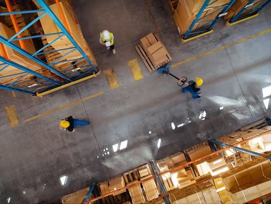 The layout of one corner of a warehouse where workers are moving products. One person is pulling a pallet of boxes.