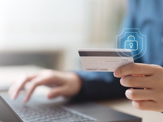 Person holding a credit card while using a laptop, with a digital lock symbol representing secure online payments.