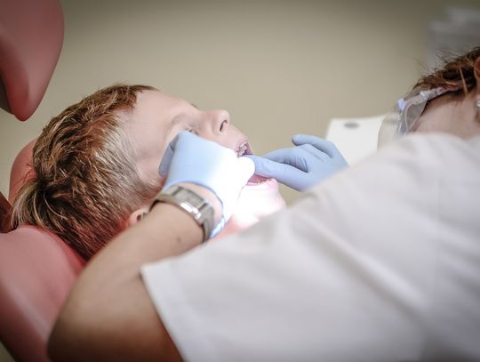 dentist looking in mouth of child