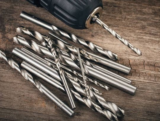 An electric drill and different sizes and shapes of drill bits for various drilling operations.