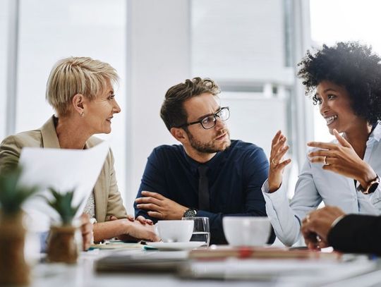 Diverse colleagues collaborating in a bright, modern office with large windows and natural lighting.