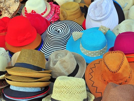 A colorful assortment of woven and patterned hats displayed together at an outdoor market or retail stall.
