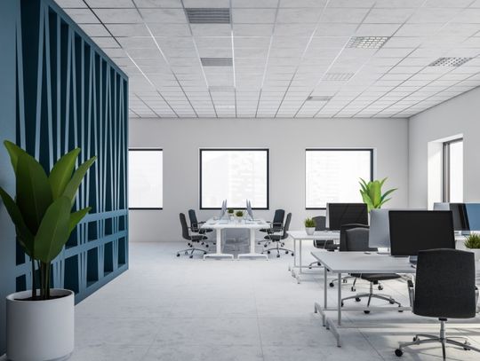 The interior of a modern office space with white and blue walls, white desks, and black desk chairs.