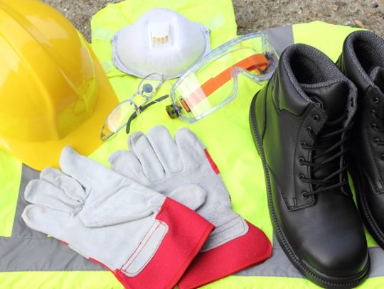 A collection of personal protection equipment including a hard hat, work vest, gloves, and a pair of boots.