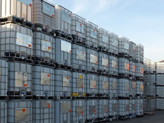 Stacks of intermediate bulk containers on pallets in an industrial yard wait to be cleaned or recycled for further use.