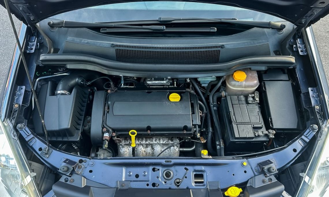 6 Essential Sensors in Trucks and What They Do Overhead view of a car engine bay with a black plastic engine cover, yellow oil cap, battery, and coolant reservoir.