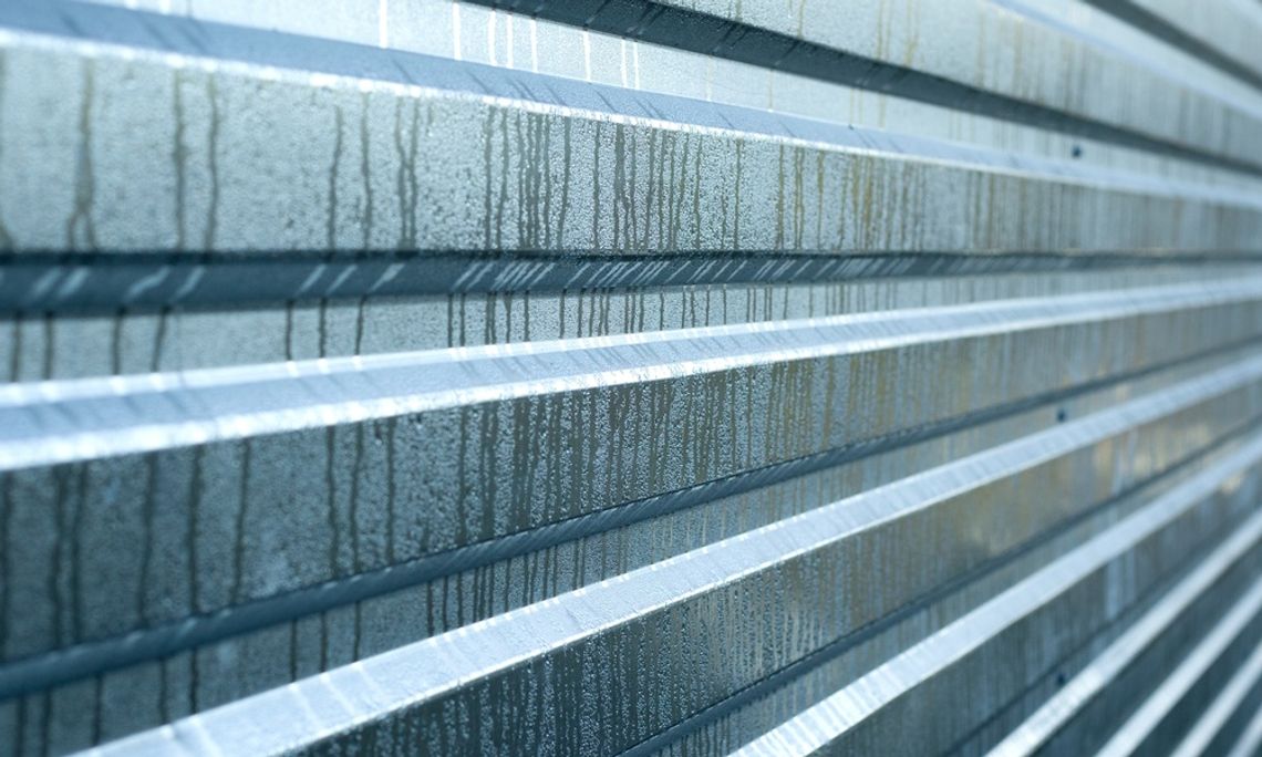 Are Metal Buildings Fit for Humid Climates? A close-up of a corrugated metal panel with condensation and vertical streaking across the surface.