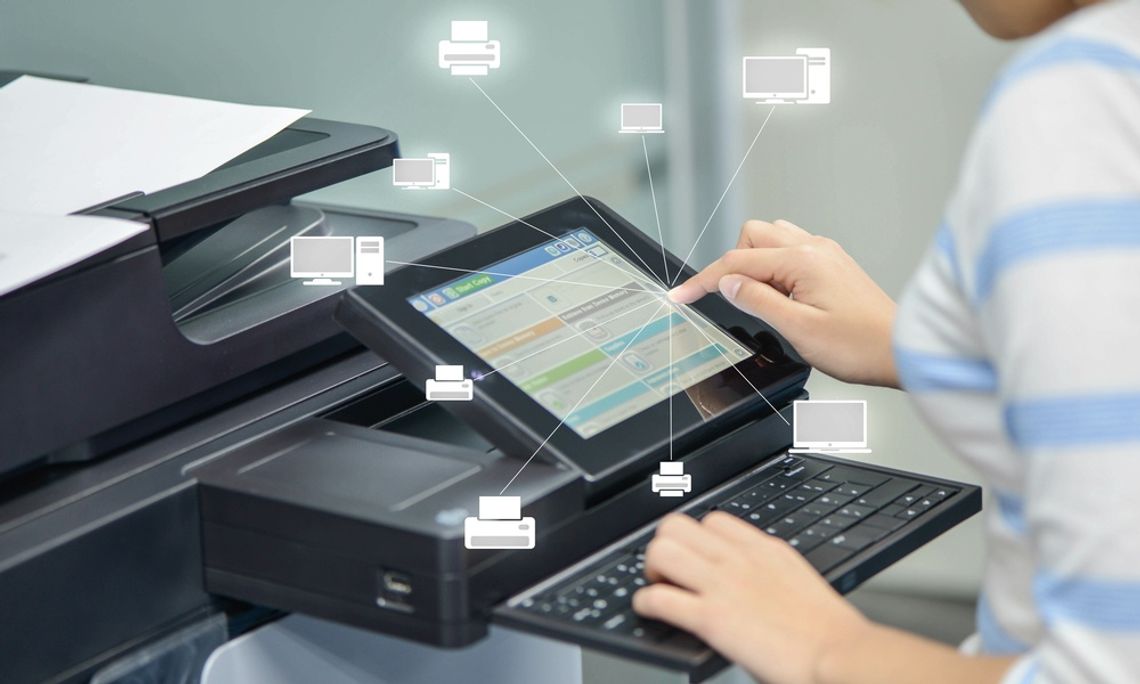 Best Practices for More Secure Cloud Printing A woman presses buttons on an office printer with a stack of papers. A glass wall is visible in the background.