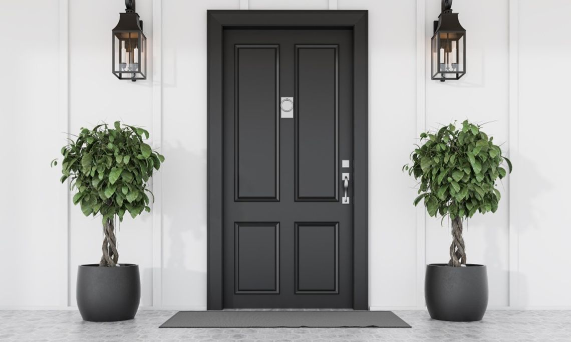 Best Ways To Strengthen Doors and Home Entry Points A black front door is situated between small potted trees in black pots and lights attached to the white siding.