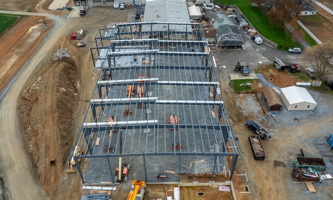 A construction site featuring the metal frame of a building. Various equipment and materials are present.