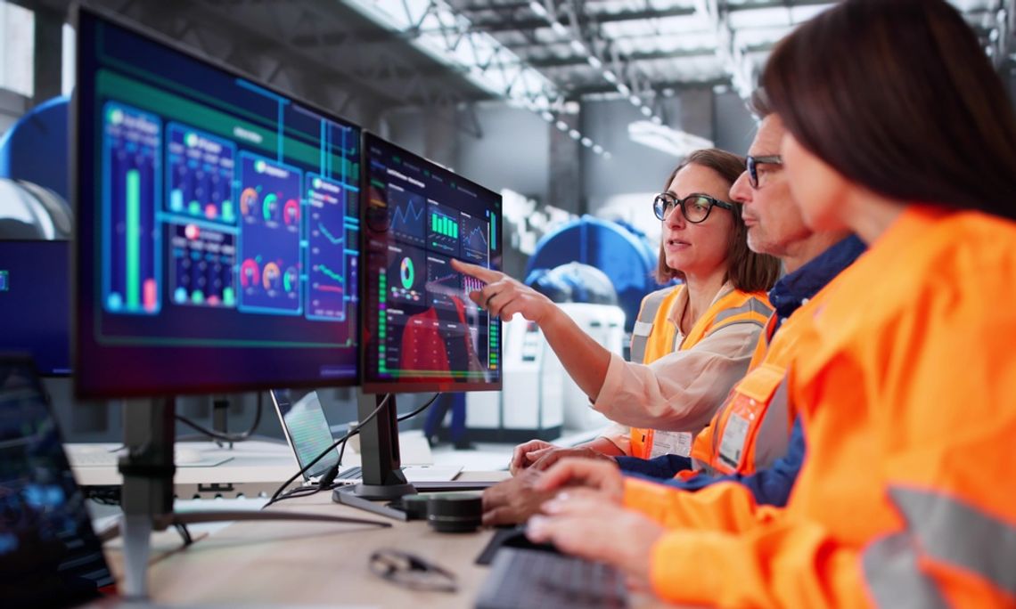 Common Mistakes When Businesses Begin To Automate A group of three engineers meeting in front of a three screen computer setup. One of them is pointing at a screen.