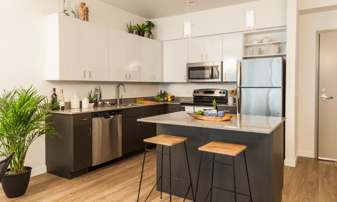 A residential kitchen with a refrigerator, an island, and multiple cabinets along the wall.