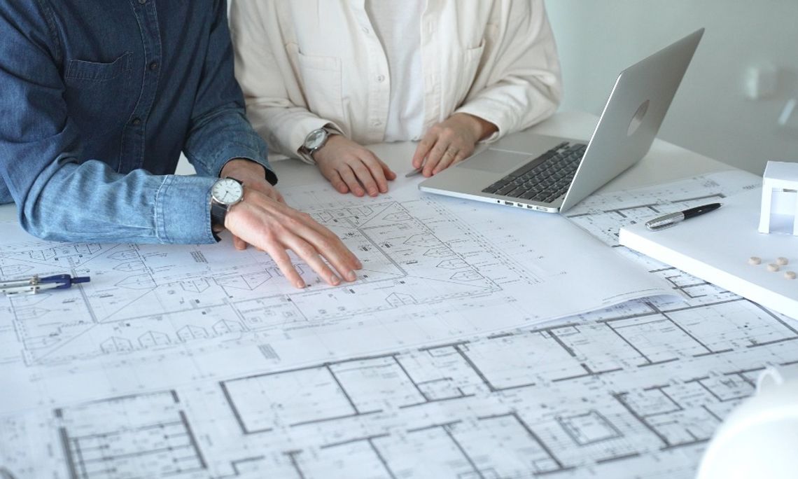 Essential Safety Systems Every Commercial Property Needs Two people are sitting at a table. There are diagrams on paper on top of the table, as well as a laptop.