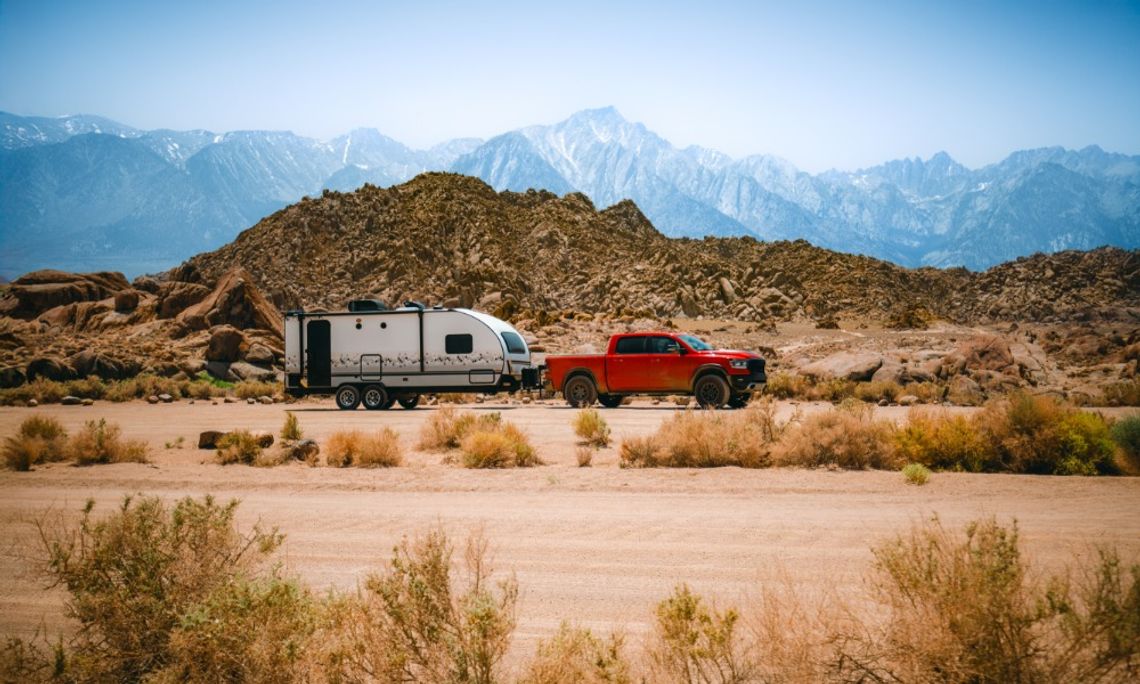 Expert Tips To Improve Travel Trailer Comfort A red pickup truck hauling a travel trailer behind it. They're traveling through the desert and mountains.