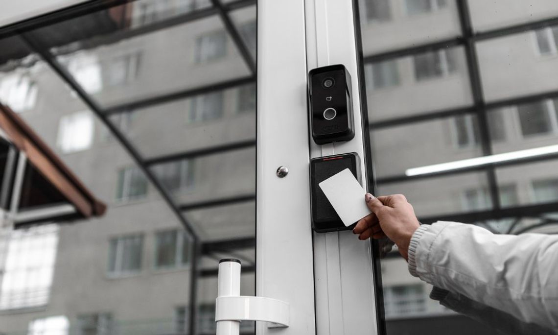 A person holding an access control keycard up to an AI sensor to gain entry to the business building.