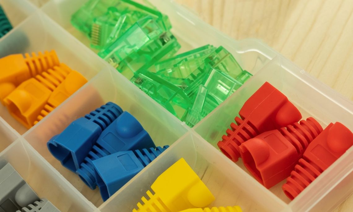 How Connector Caps Improve System Reliability A close-up view shows a plastic organizer filled with various plastic connector caps in different colors.