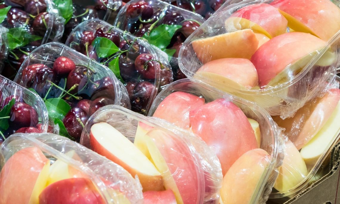 Plastic containers hold sliced red apples and whole cherries; no labels are visible on the packaging.