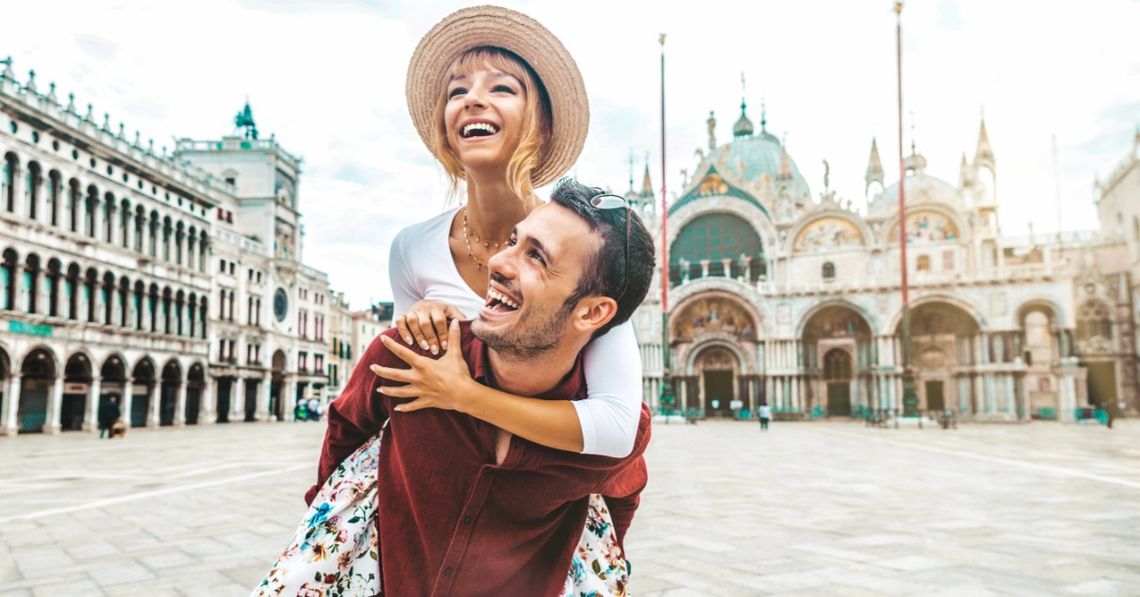 How To Avoid Rushing Through a European Vacation A man gives his female partner a piggyback ride through a European city center. They smile as they take in the sites.