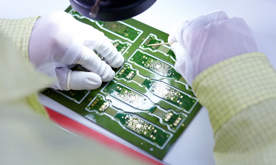 How To Choose Metal Foils for Flexible Electronics A point-of-view close-up of a person with gloves working on a green flexible electronic circuit board.
