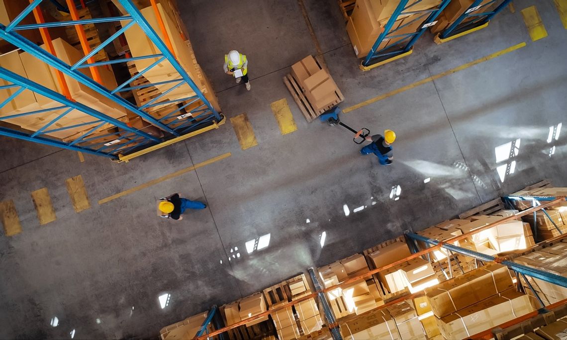 The layout of one corner of a warehouse where workers are moving products. One person is pulling a pallet of boxes.