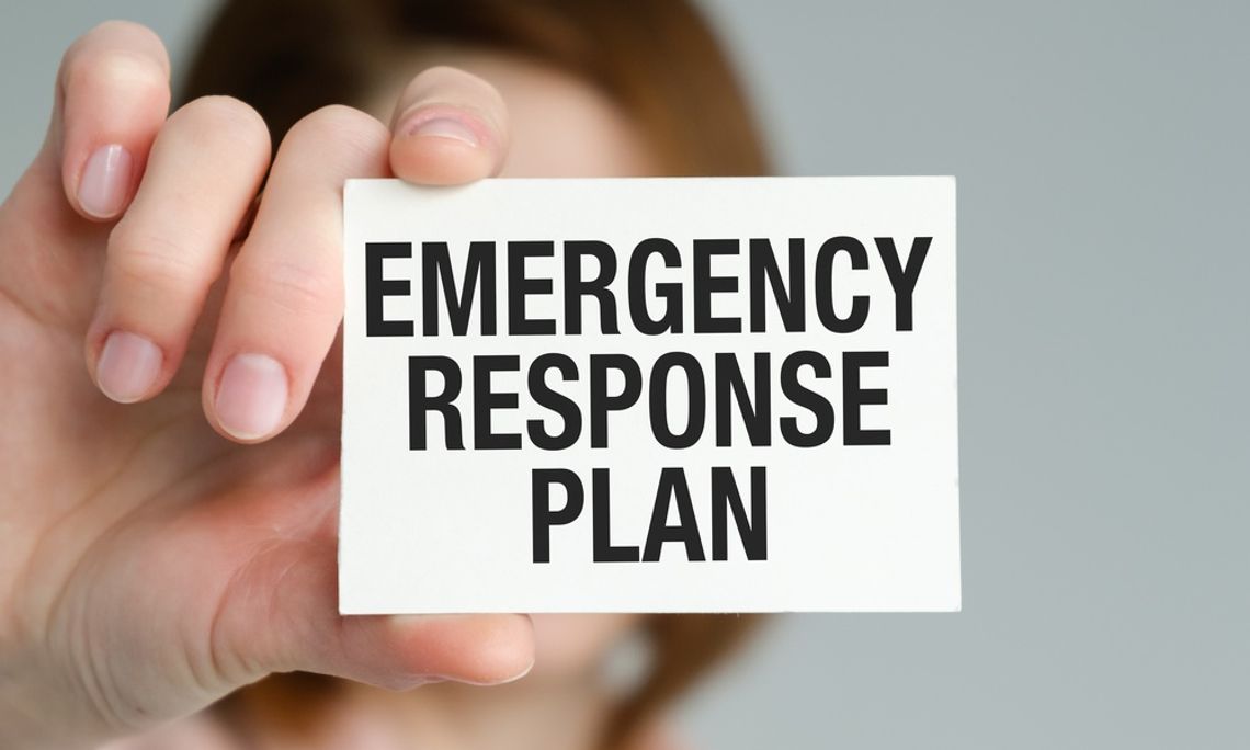 A person holds a card labeled "Emergency Response Plan," symbolizing workplace safety and organized emergency preparedness.