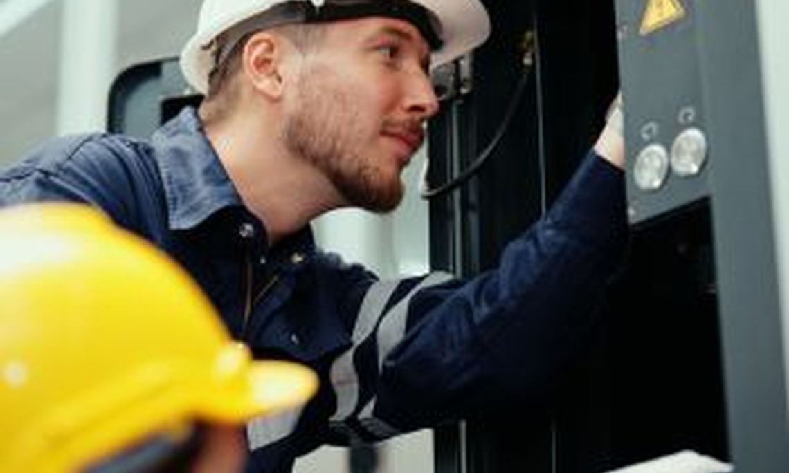 How To Ensure Electrical Safety in Healthcare Facilities Two male production engineers in safety wear are assisting with the adjustment and maintenance of a machine in the facility.
