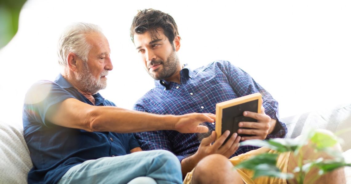 How To Help a Loved One Navigate Medical Appointments Two men seated on a couch look at a tablet together while the older man reaches toward its screen.