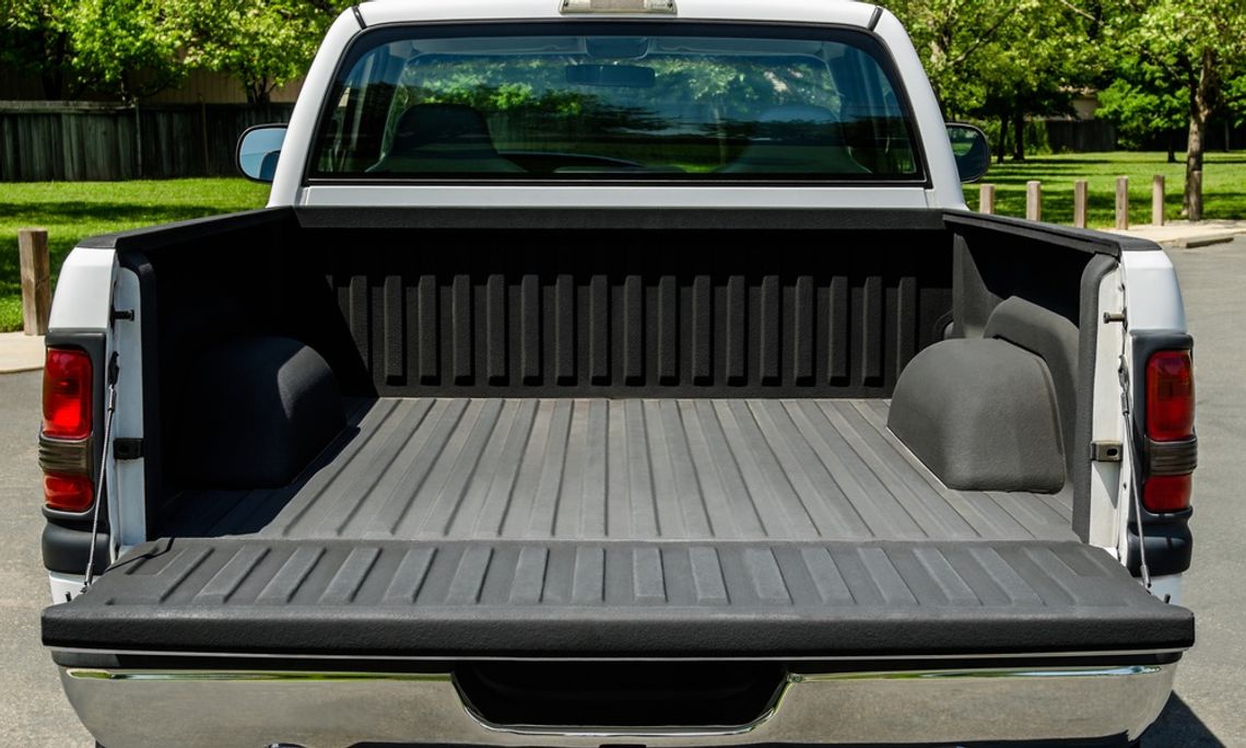 How To Make A Pickup Truck More Functional A white pickup truck with its tailgate down. The truck bed is empty and has an upgraded liner installed onto it.