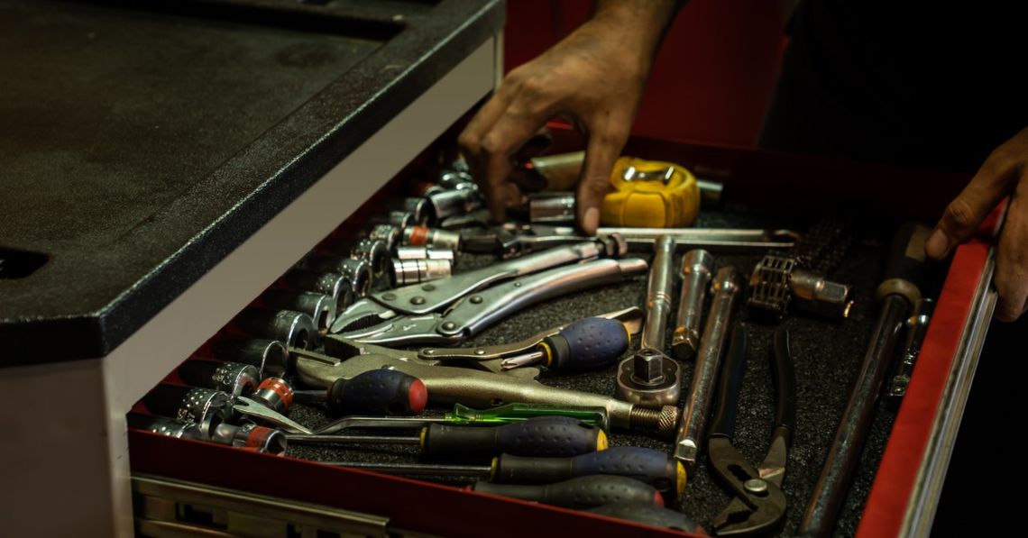 How To Plan a Truck Project You Can Actually Finish A mechanic reaches into an open tool chest packed with sockets, screwdrivers, wrenches, pliers, and a yellow tape measure.