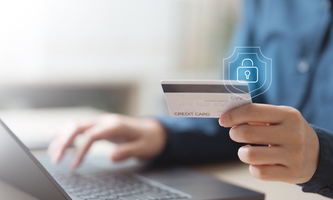 How To Protect Yourself From Financial Fraud Person holding a credit card while using a laptop, with a digital lock symbol representing secure online payments.