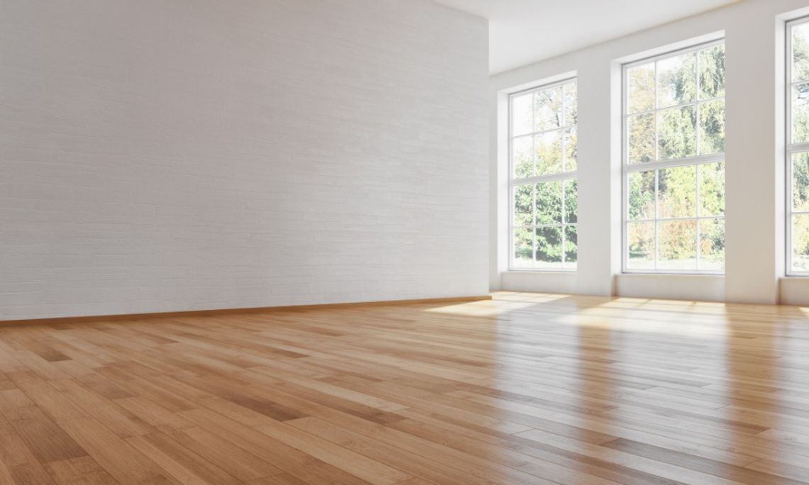 How You Can Better Protect Your Home’s Floors A closeup on the hardwood flooring of house's main room. The walls and ceiling of the room are an off-white color.