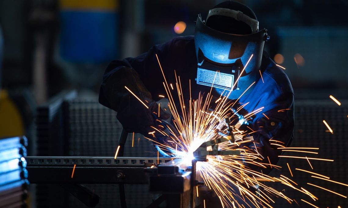 A person who is wearing a protective mask is using an arc welder on a piece of material.