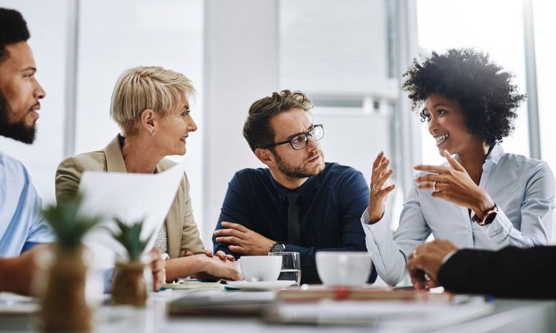 Diverse colleagues collaborating in a bright, modern office with large windows and natural lighting.
