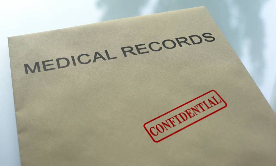 A tan folder labeled Medical Records with a red confidential stamp resting on a reflective glass tabletop.