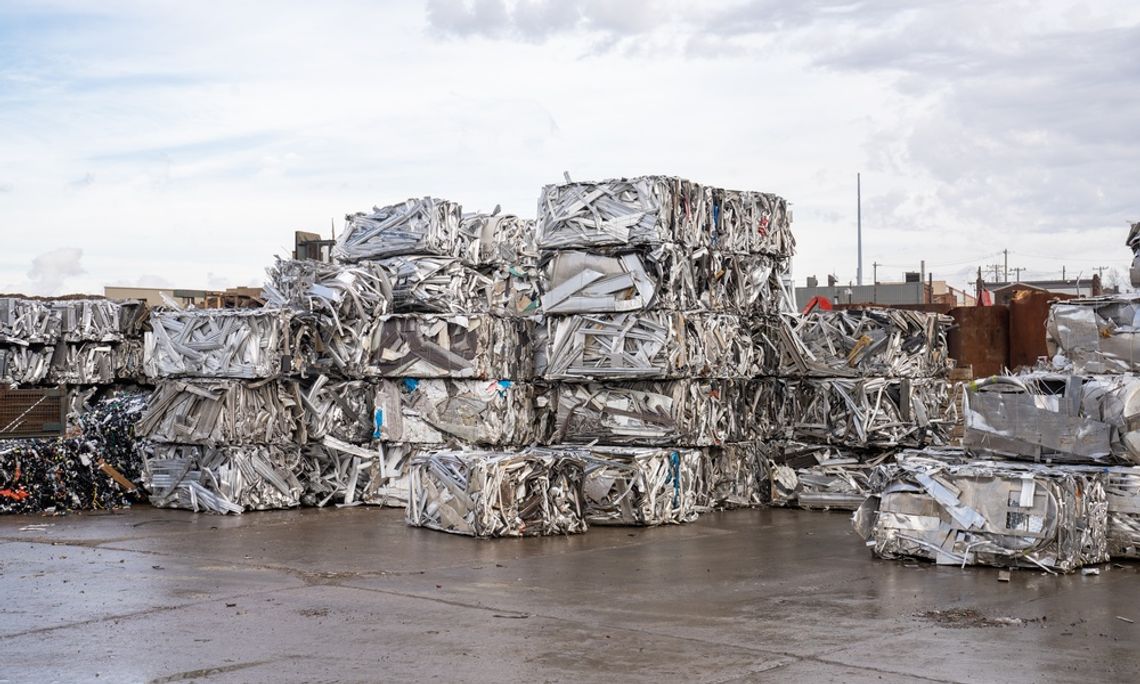 Numerous bales of aluminum and metal scrap are stacked on top of each other outside in a recycling yard.