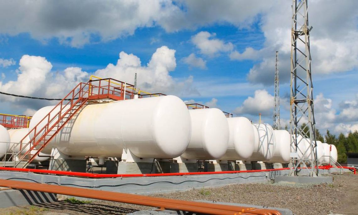 Multiple gasoline storage tanks sit horizontal and are all next to each other on a large concrete slab.