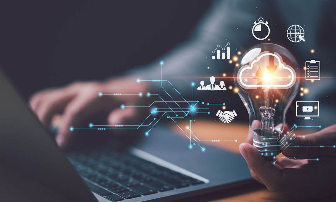 Tech Solutions Making Lighting More Eco-Friendly A hand holding a glowing light bulb over a digital network graphic with blue icons and blurred light graphics.
