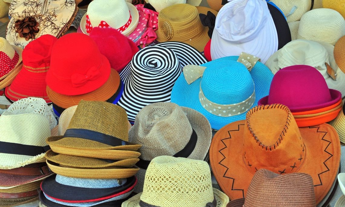 A colorful assortment of woven and patterned hats displayed together at an outdoor market or retail stall.