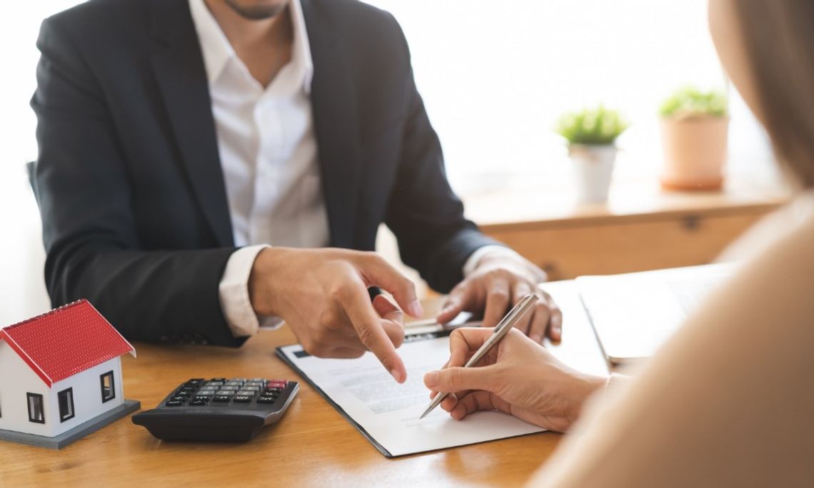 The Biggest Mistakes Portland Rental Owners Make A close-up of a hand holding a pen over a document on a desk in front of a man pointing at a line on the document.